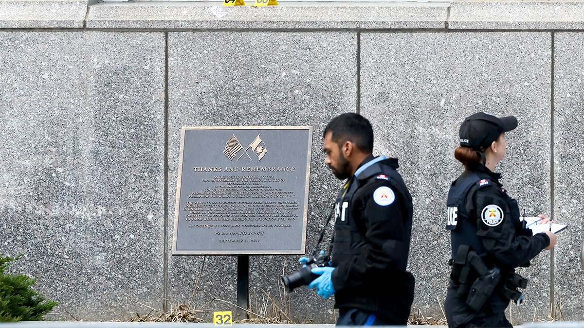 Police officers gather outside a secured diplomatic building in downtown Toronto following reports of gunfire.