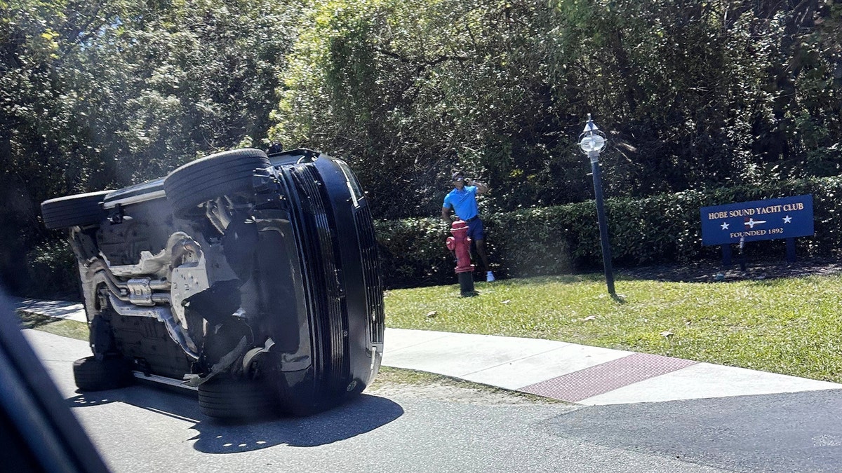 Golfer Tiger Woods stands by his overturned vehicle in Jupiter Island Florida