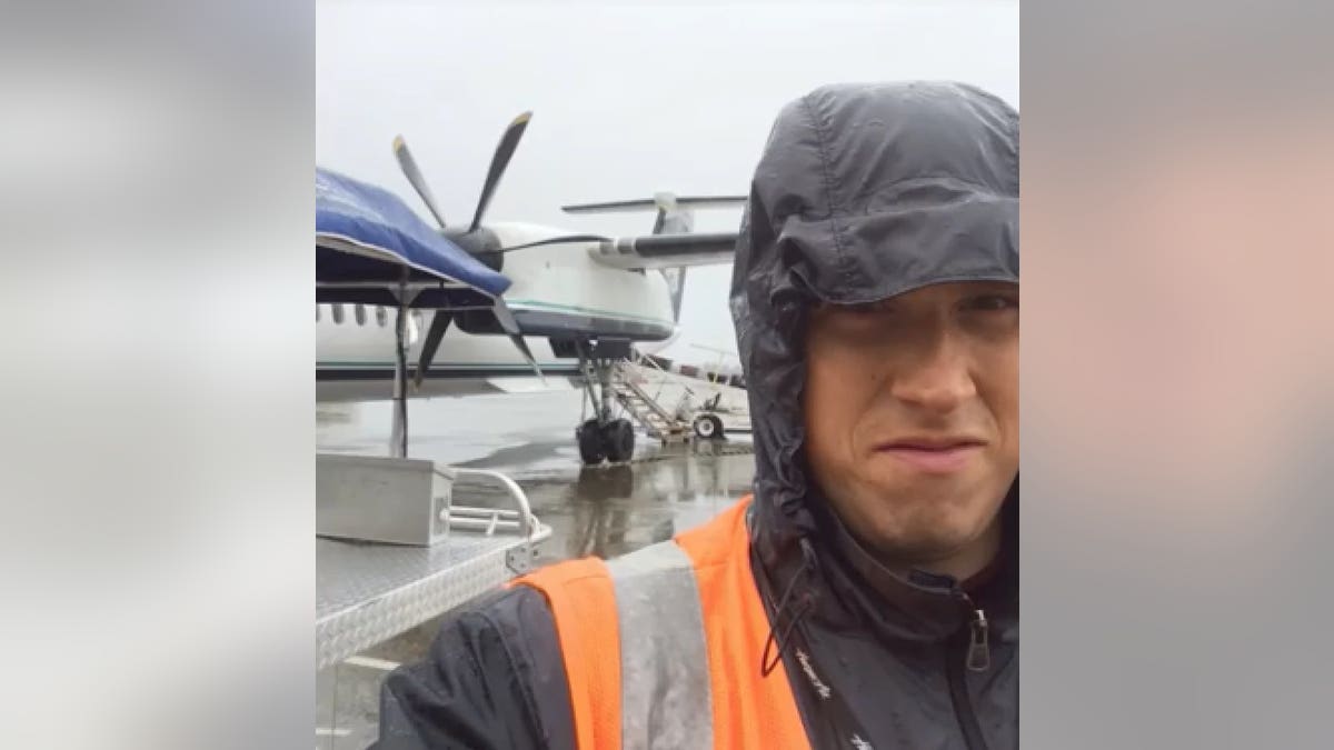 Richard Russell making a funny face while trying to shield himself from the rain at the airport.