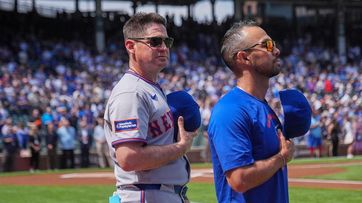 New York Mets manager Carlos Mendoza standing during the Star-Spangled Banner before a baseball game
