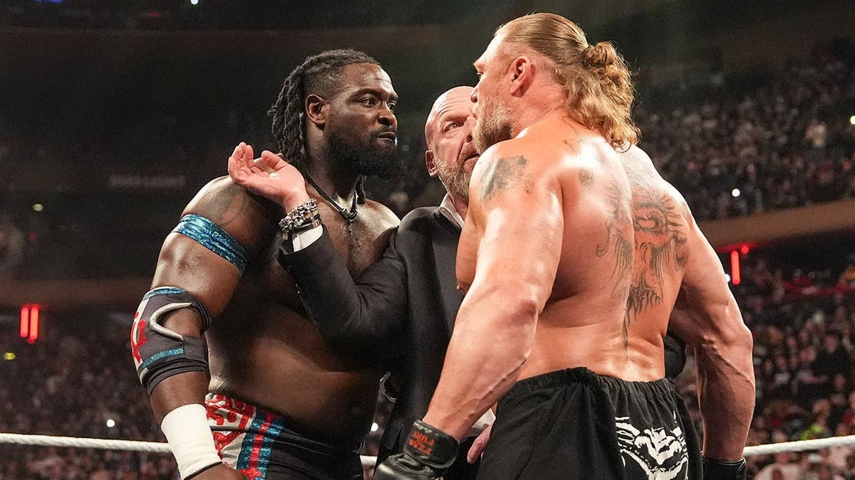 Oba Femi and Brock Lesnar face off in the ring with Triple H during Monday Night RAW at Madison Square Garden