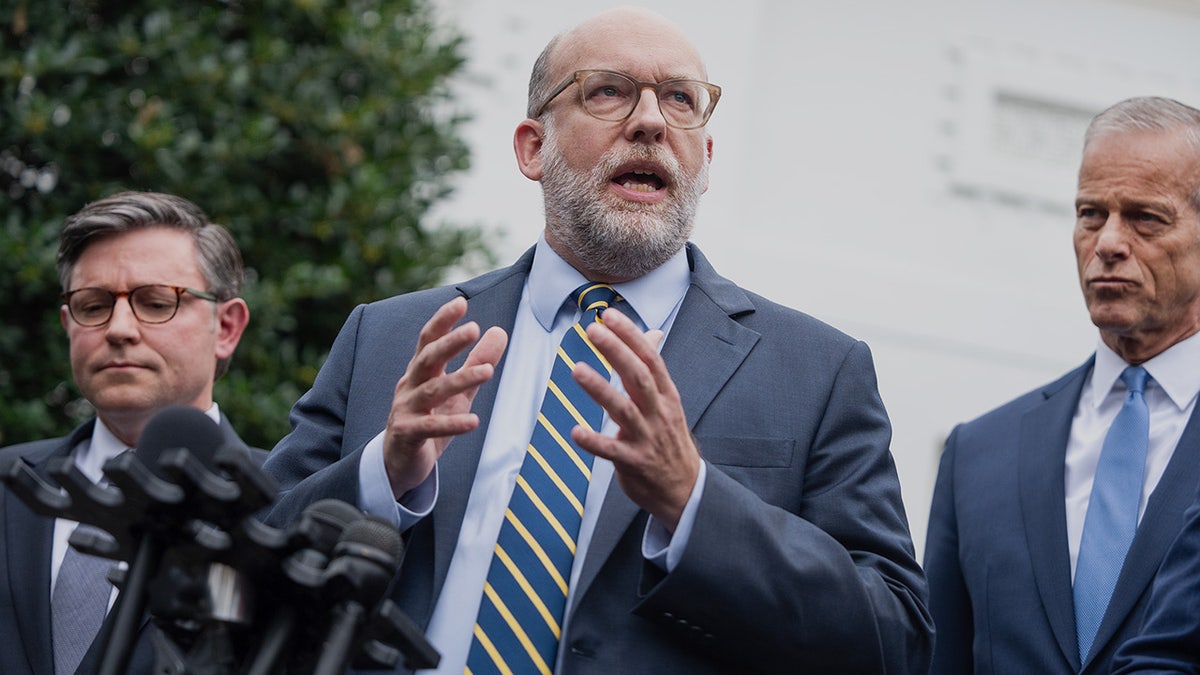 Russell Vought speaking at a news conference at the White House with Mike Johnson and John Thune