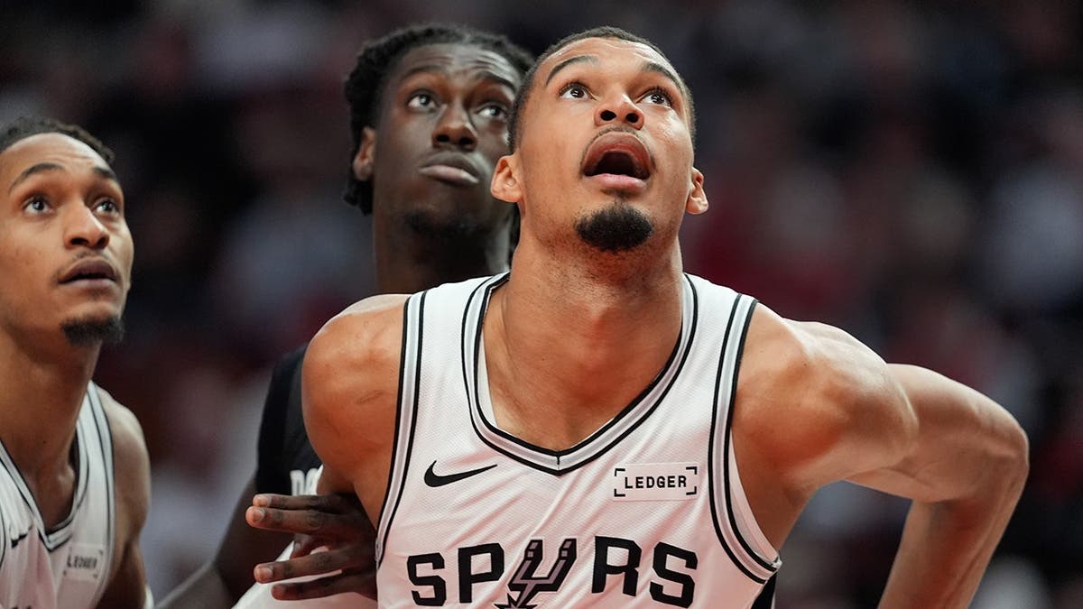 San Antonio Spurs forward Victor Wembanyama and Portland Trail Blazers guard Sidy Cissoko watching for a rebound during a basketball game