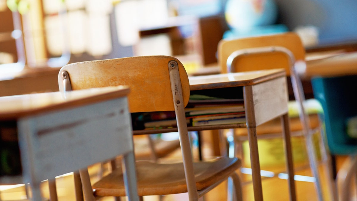 A U.S. school classroom with empty wooden desks and chairs.