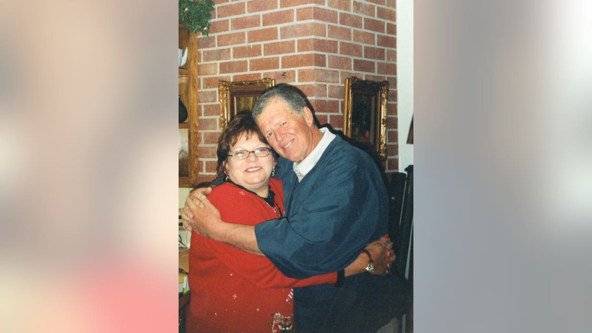 Deb Proctor in a red sweater holding onto Jeff Walton in a blue denim shirt.