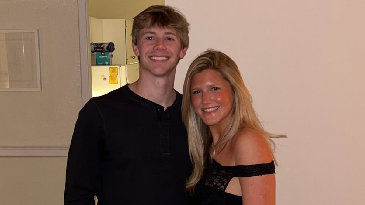 Brandon Towers and Whitney Robeson are both wearing black and posing in front of a white wall in an undated family photo.