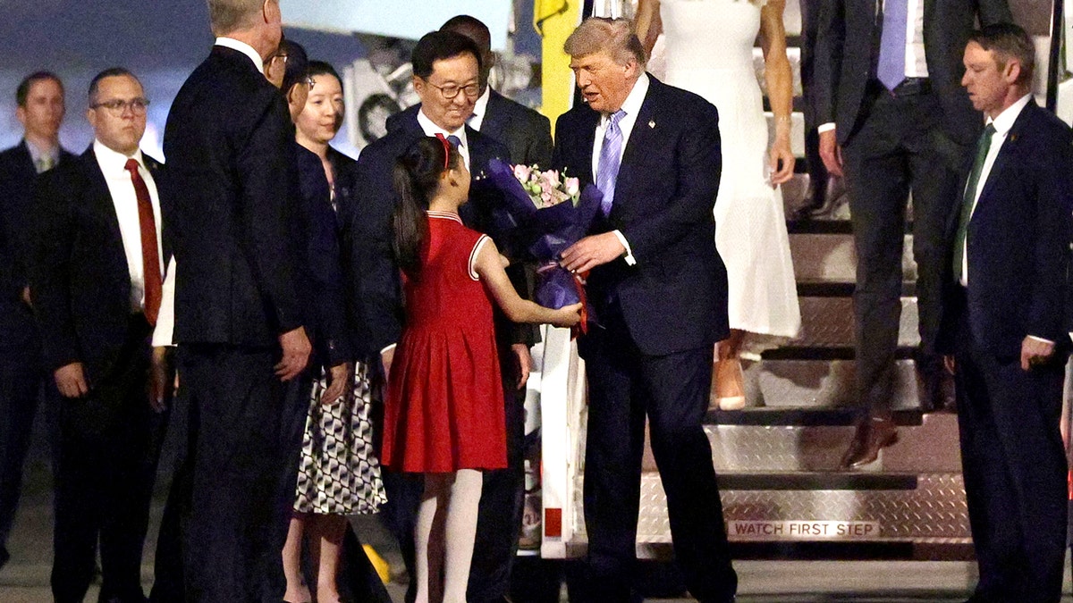 Trump receives a flower bouquet from a young girl in china