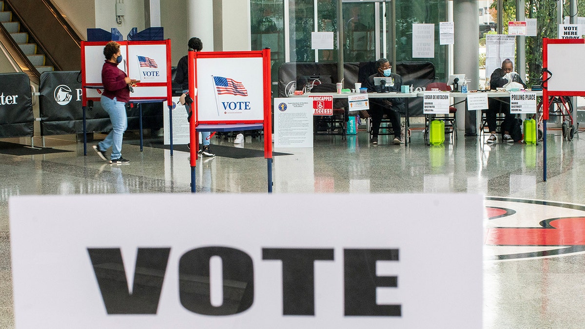 A woman walking to cast her ballot after filling it in a privacy booth