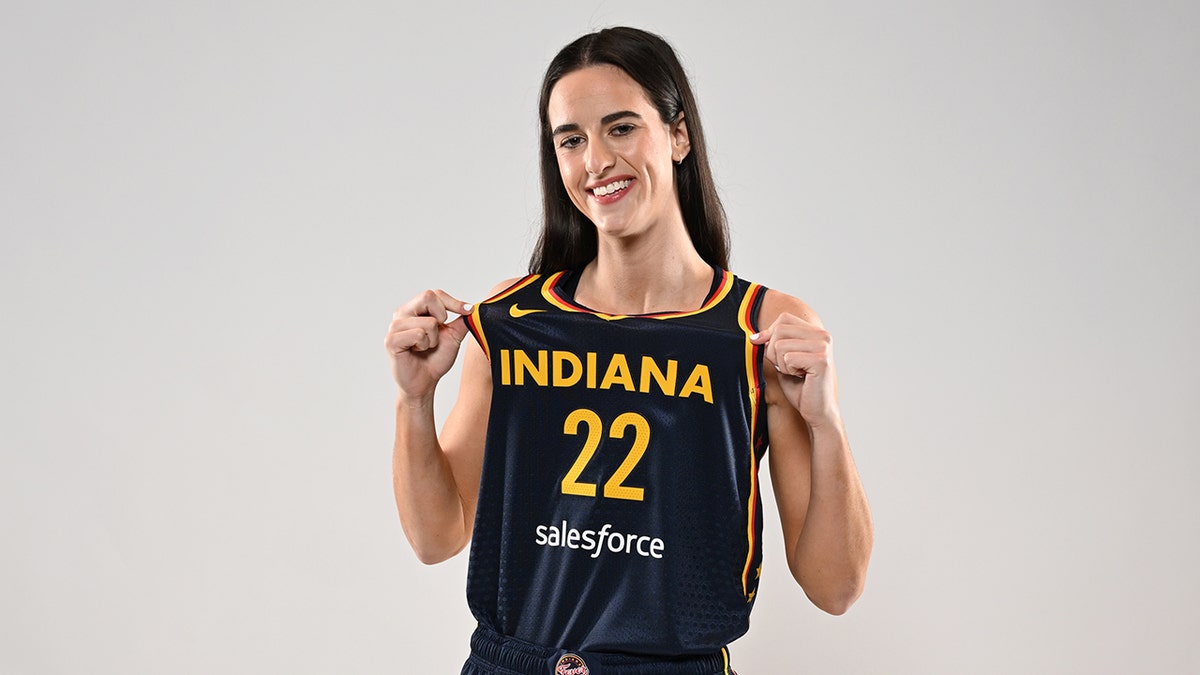 Caitlin Clark posing with Indiana Fever jersey at Gainbridge Fieldhouse
