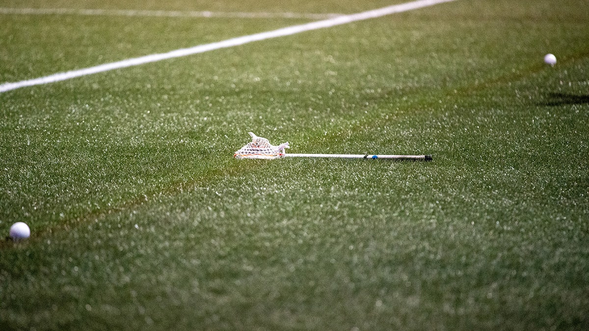 A broken lacrosse stick lying on the sideline.