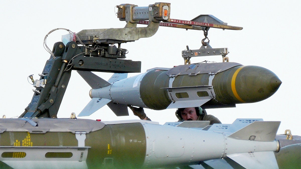 Military personnel loading munitions onto a U.S. Air Force B-1 bomber on a runway at RAF Fairford