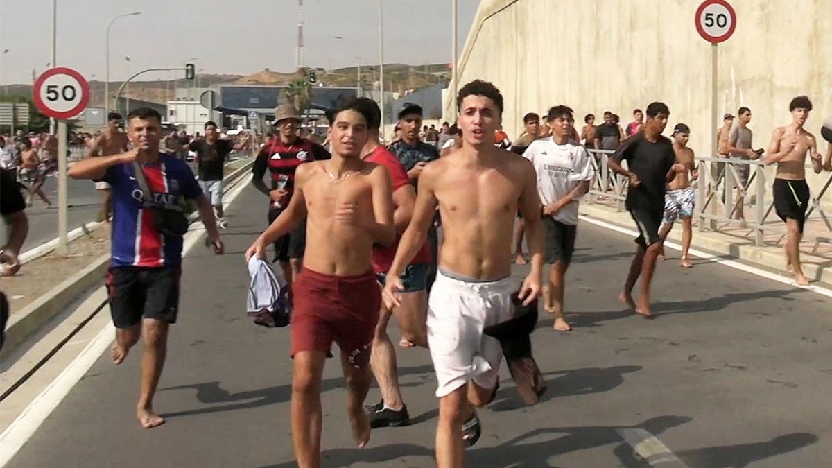 Migrants run and cheer as they cross on foot into the North African enclave of Ceuta from Morocco, after swimming over from the Moroccan side and overwhelming police at the city's breakwater, according to Spain's Guardia Civil, in Ceuta, Spain, July 30, 2026.