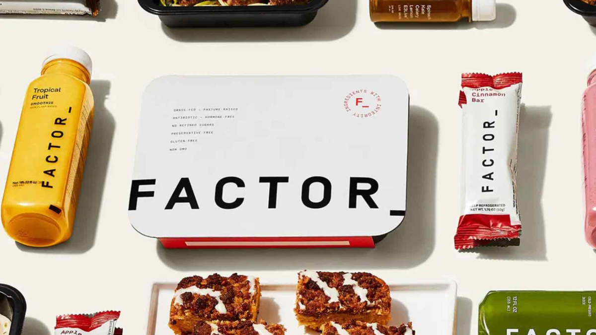 From left: jug of orange juice, boxed meal, factor meal bar. Background: light cream.