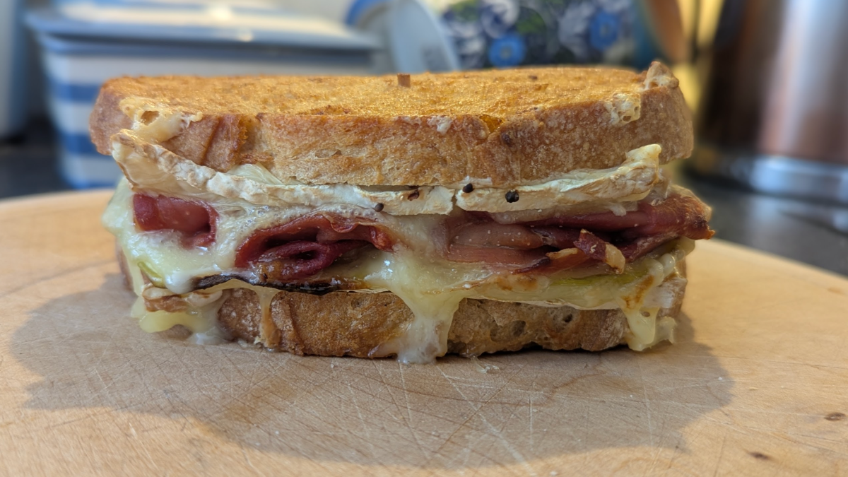 grilled cheese with cured meat on a cutting board