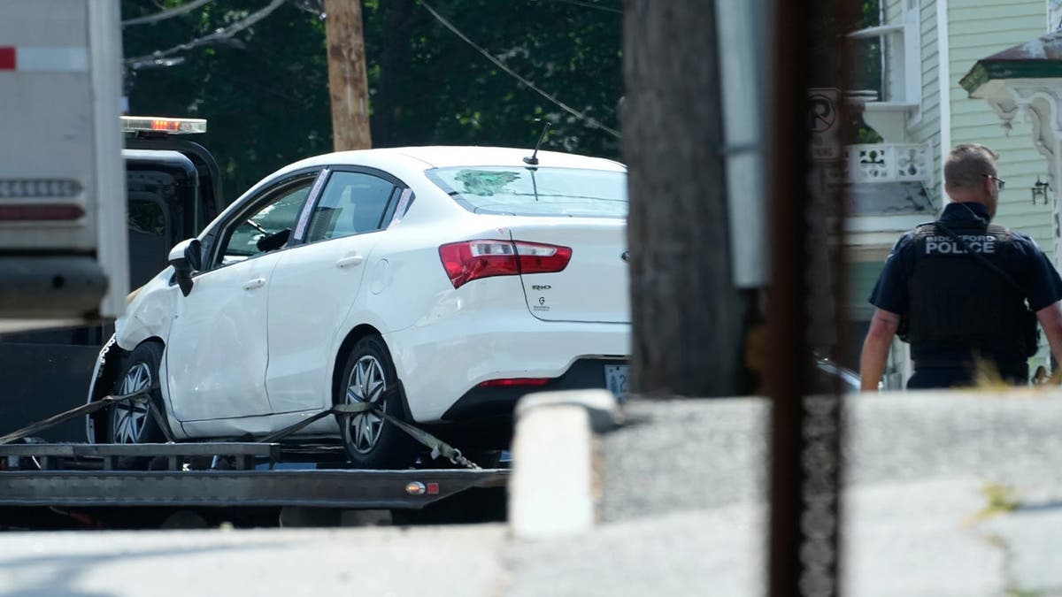 A white car on a flatbed truck