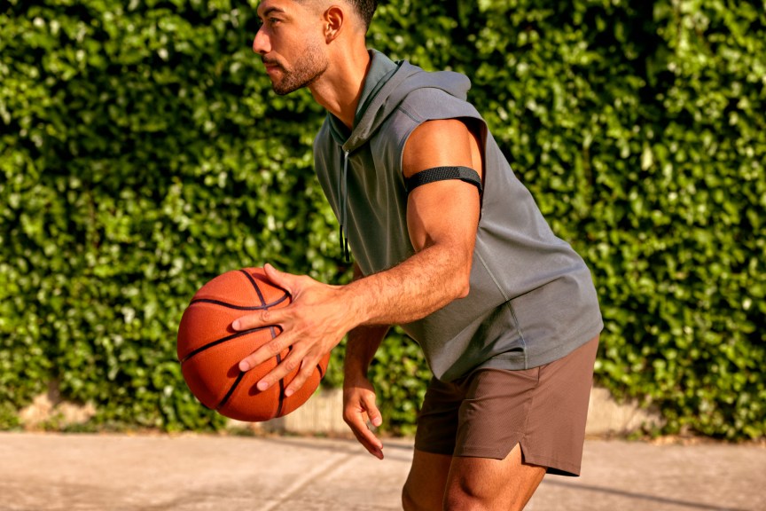 A person holding a basketball while wearing a black Cirqa upper-arm band.