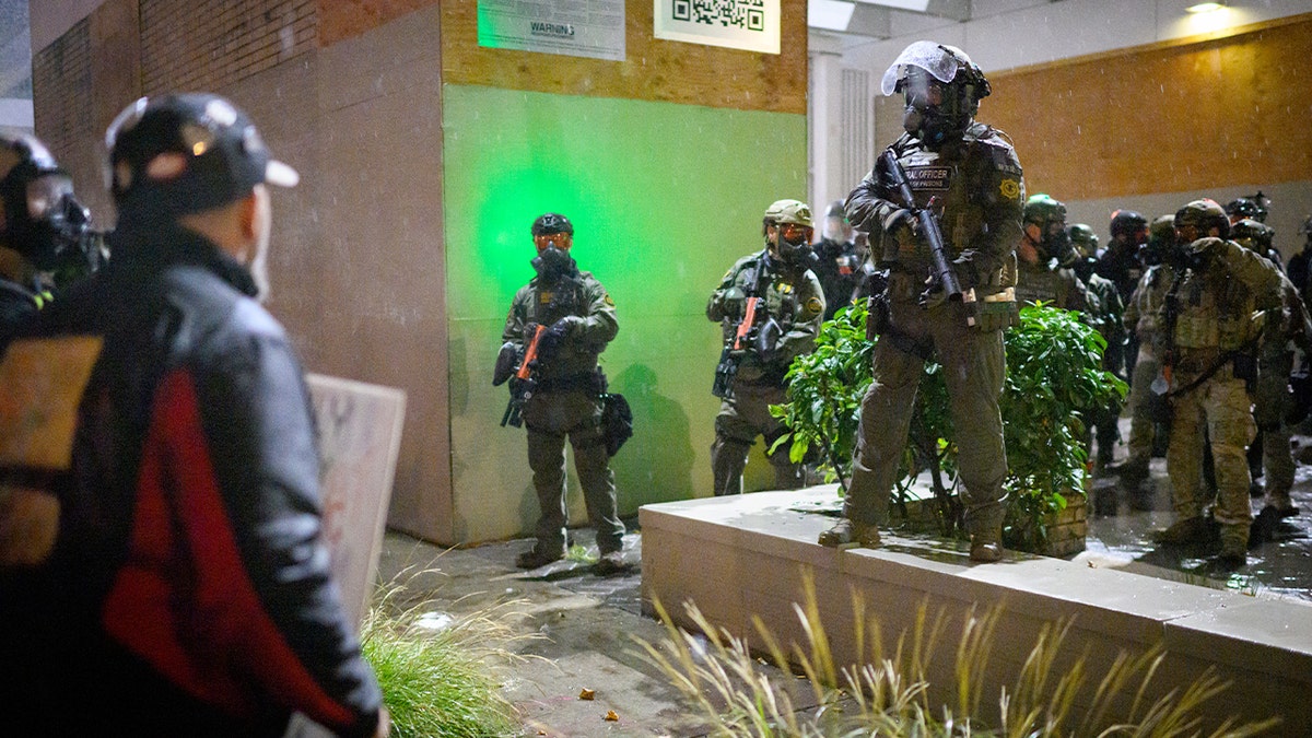 Demonstrators confront law enforcement outside a federal immigration facility during a nighttime protest in Portland.