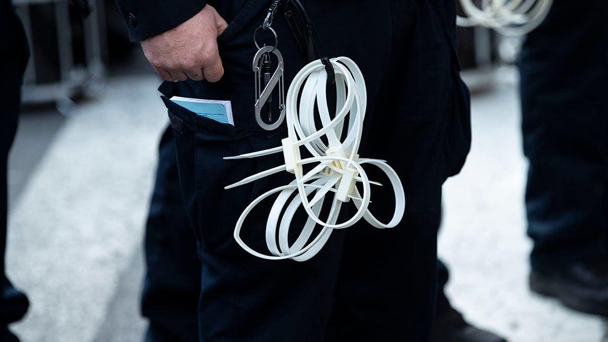 NYPD officers stand with zip tie handcuffs in Manhattan.