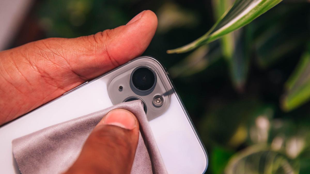 Wiping down the camera lens with a gentle cloth.