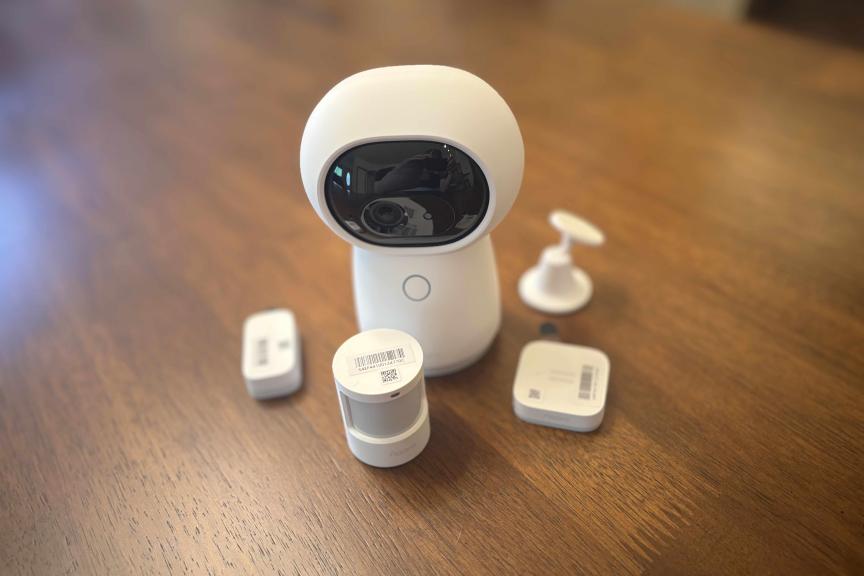 Aqara white camera system on a wood table.