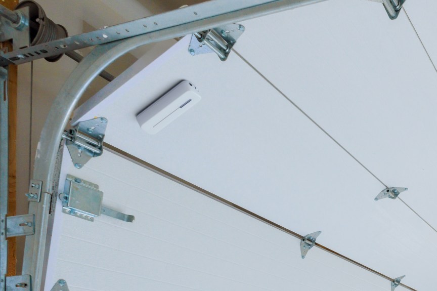 Abode sensor on a white garage door. 