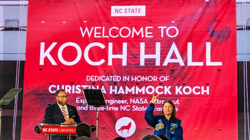 NASA astronaut Christina Koch (right) does the Wolfpack hand sign on stage next to NCSU chancellor Kevin Howell