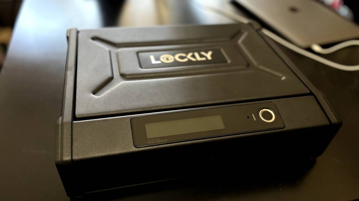 A Lockly smart safe sits on a black office desk.