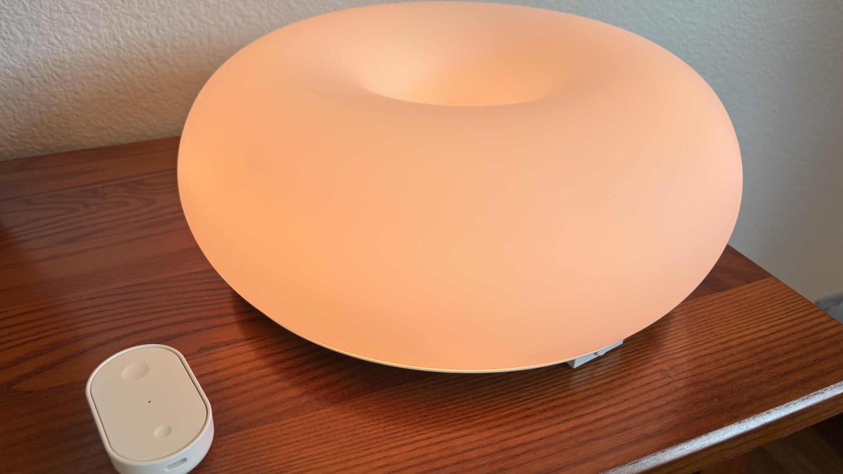 Ikea smart lamp glowing orange on a table.