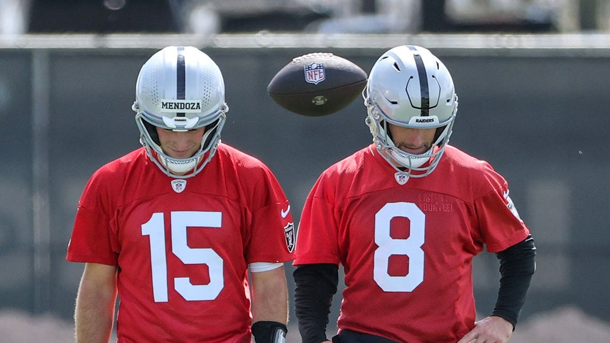 Fernando Mendoza and Kirk Cousins walk on a field during a Las Vegas Raiders OTA workout.