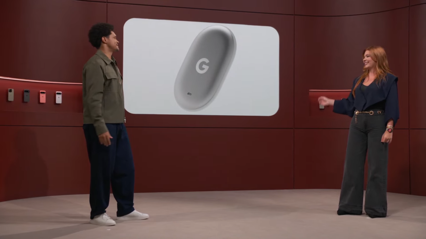 A man and woman stand in front of a screen that displays a Google Tag.