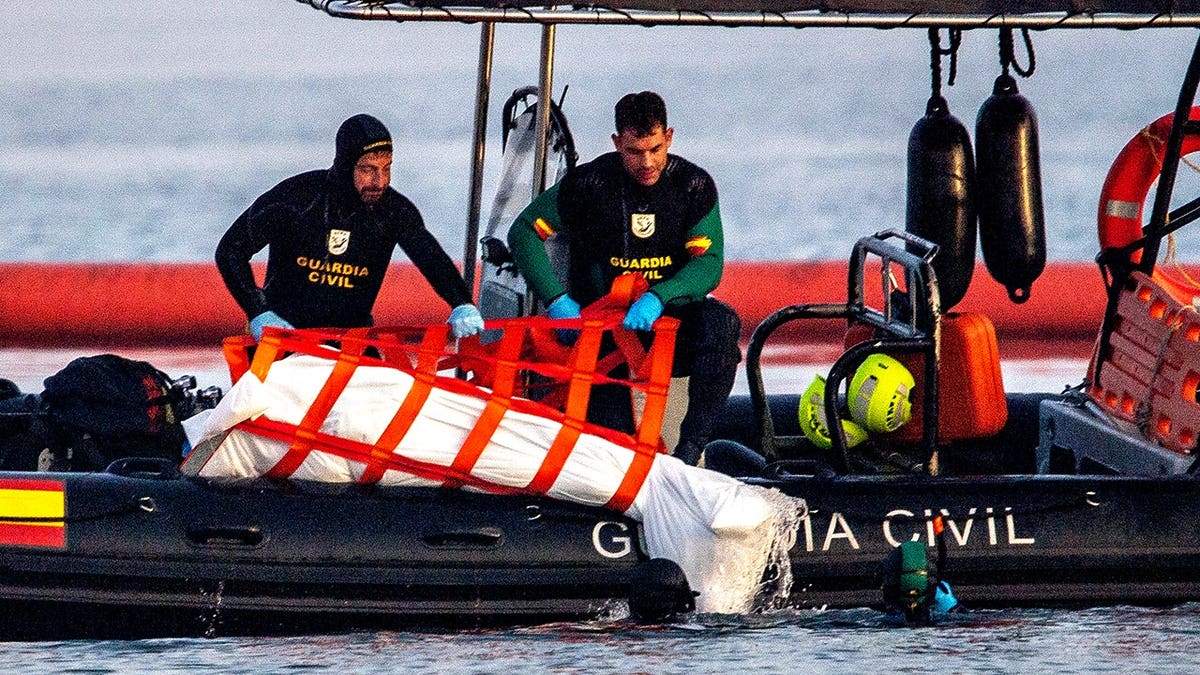 Guardia Civil officers recover a migrant's body from water in Ceuta.