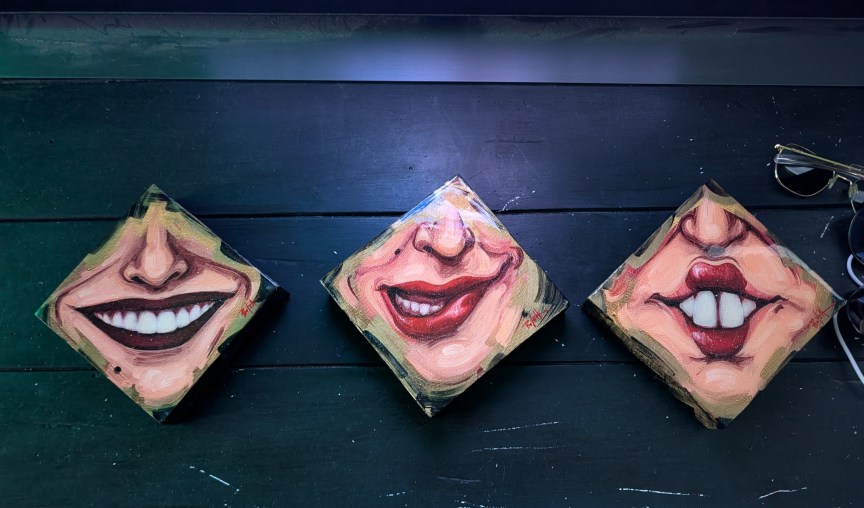 An artist's piece showing three diamonds with noses and smiling mouths in them
