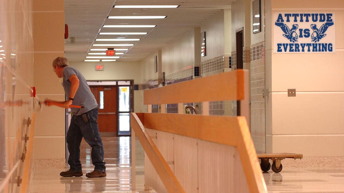 Larry Goodhart, a custodian, shines walls inside Exeter High School.