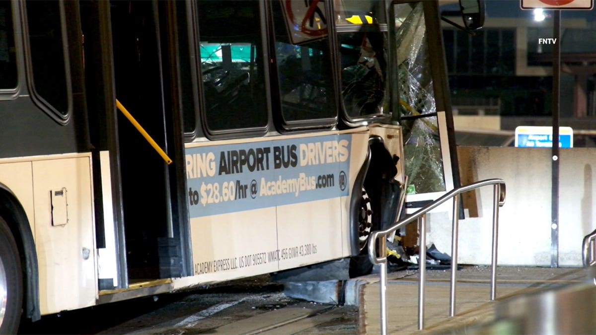 crumbled front end of bus with shattered glass and debris on the ground