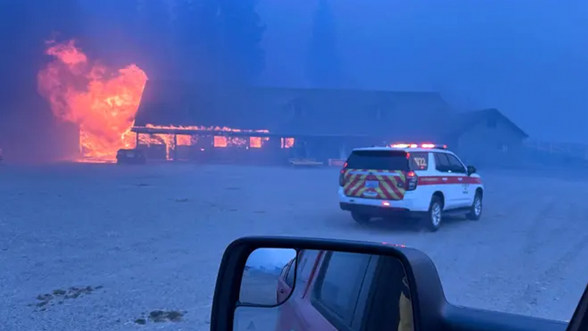 A home burns as firefighters respond during the fast-moving Spokane-area wildfires