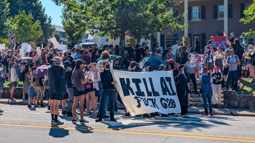 UNC-Chapel Hill students and local residents protested Big Tech outside the G20 forum. A big sign reads: Kill AI, Fuck G20