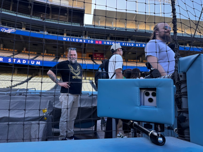 An iPhone 18 Pro Max slid into  protective padding in front of netting protecting stadium attendee seats.