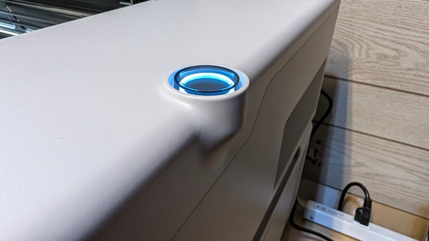The edge og a gray laser with a molded power button glowing blue