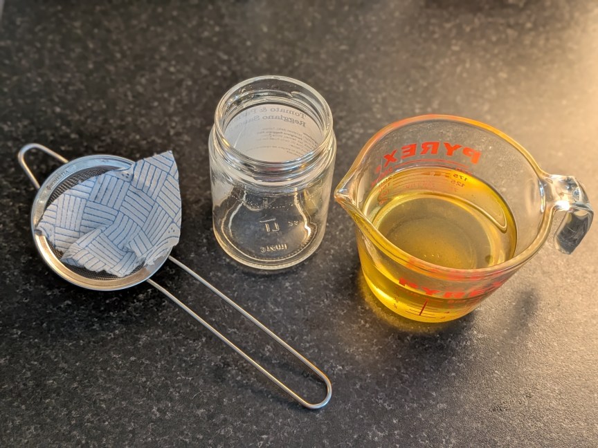 strainer har and measuring cup of oil on table