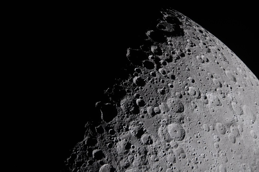 Closeup photo of the moon showing geological features between the light and dark portions of the surface.
