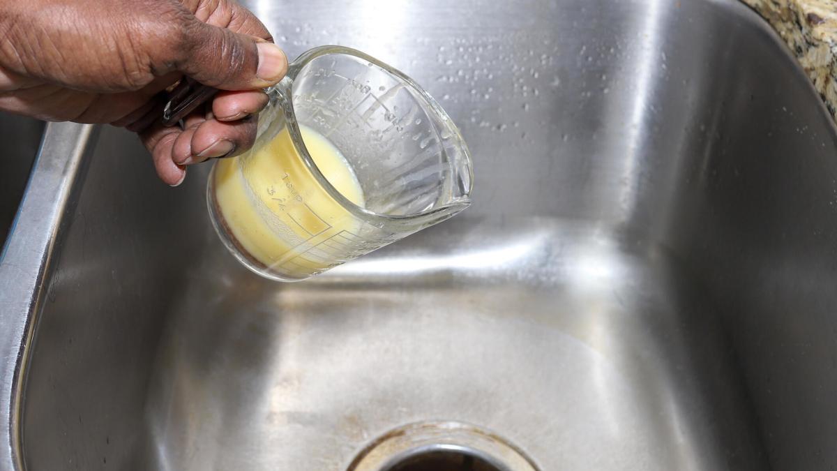 person pouring butter down sink