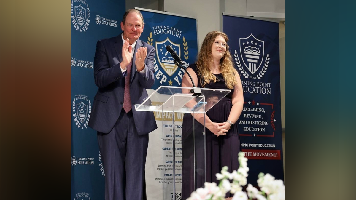 Dr. David Arnott and a Turning Point Education representative stand at a podium during an event.